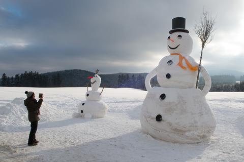 Eine Frau fotografiert einen 6,50 Meter großen Schneemann. Archivfoto: dpa