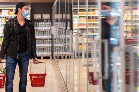 Ein Kunde geht in einem Supermarkt einkaufen und trägt dabei eine Maske. Die staatlich verordnete Maskenpflicht beim Einkaufen fällt in weiten Teilen Deutschlands weg. Foto: dpa