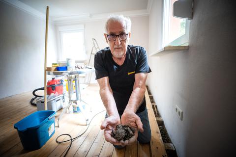 Manfred Menningen im Wohnzimmer seines Hauses, mit Kohleschlacke in der Hand.  Foto: Lukas Görlach