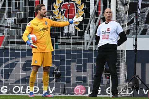 Ein Mann hat sich beim Spiel der Eintracht gegen Freiburg am Torpfosten befestigt. Torwart Kevin Trapp ist wenig amüsiert. Foto: dpa/Arne Dedert