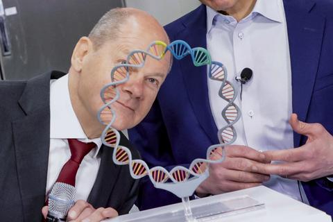 Bundeskanzler Olaf Scholz schaut bei seinem Besuch im Biontech-Werk in Marburg durch ein stark vergrößertes Modell eines Plasmids. Hinter ihm steht Biontech-Chef Uğur Sahin. Foto: Sascha Kopp / VRM Bild